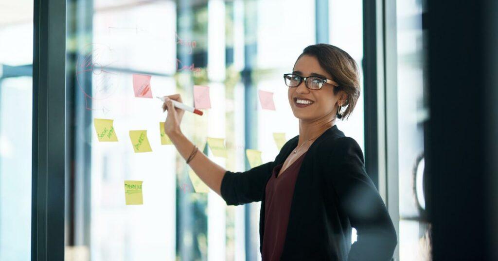 office woman standing at whiteboard smiling and looking off camera